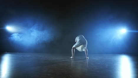 Modern-girl-dancer-in-a-white-short-dress-performs-plastic-beautiful-dramatic-dances-running-across-the-stage-falling-to-the-floor-and-spinning.-Lanterns-and-smoke.